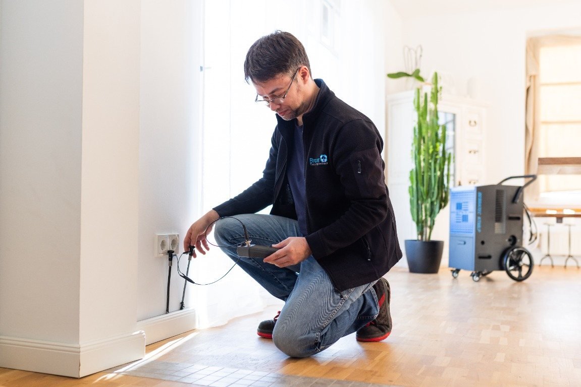 Leckorter von Brauer misst mit Elektroden die Feuchtigkeit an der Wand neben einer Steckdose